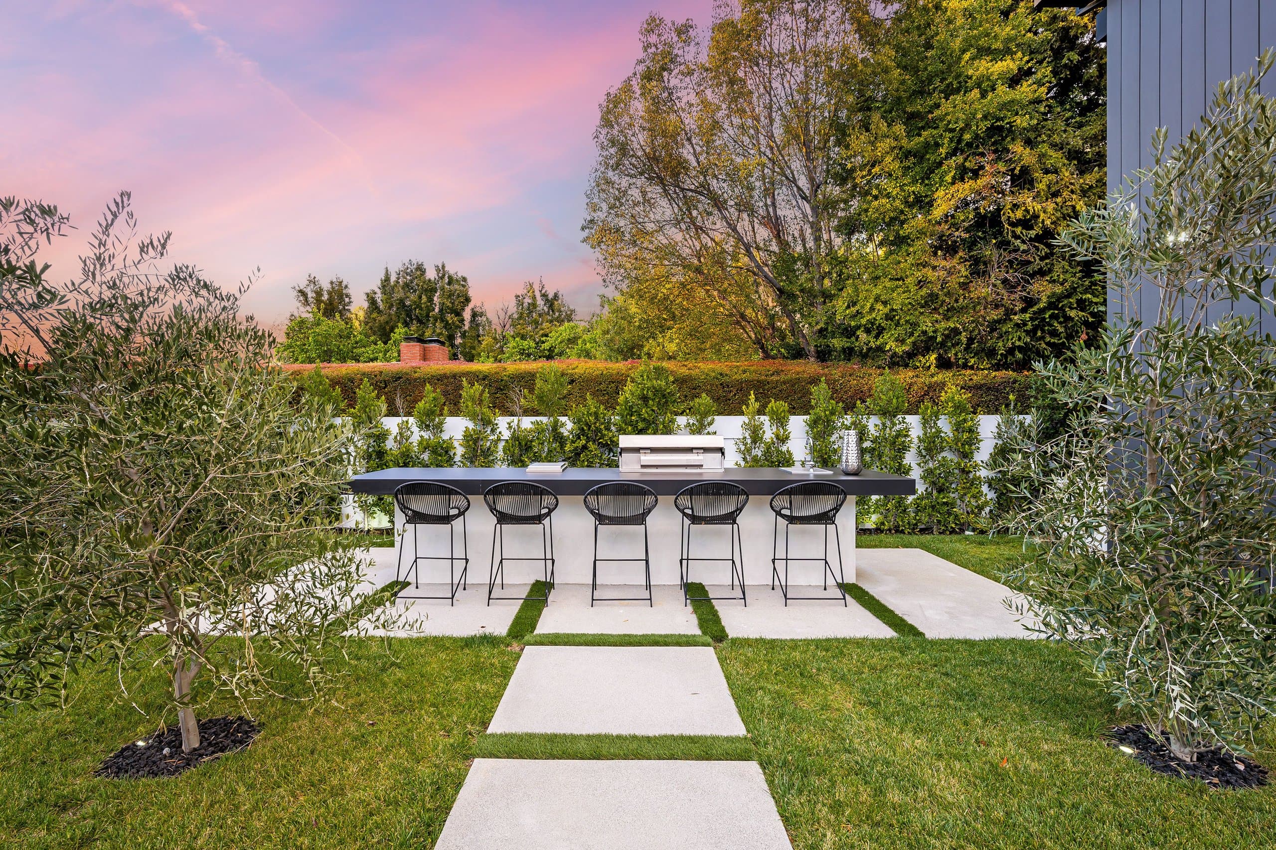 Stone entry walkway flanked by clipped box hedges at a white modern farmhouse