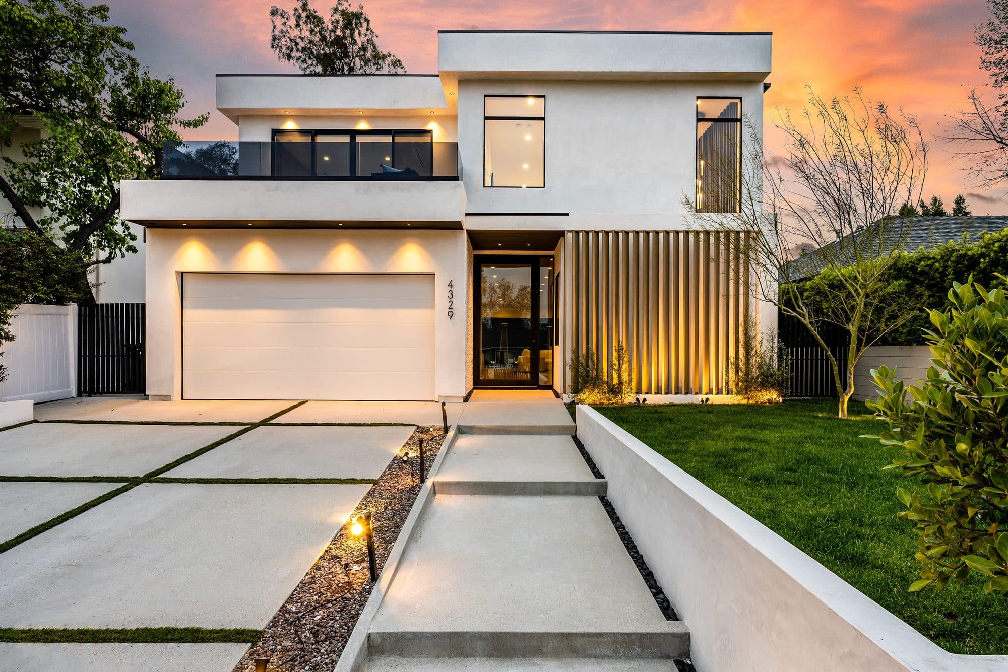 Floating concrete steps with decorative rock and integrated lighting at a white modern home