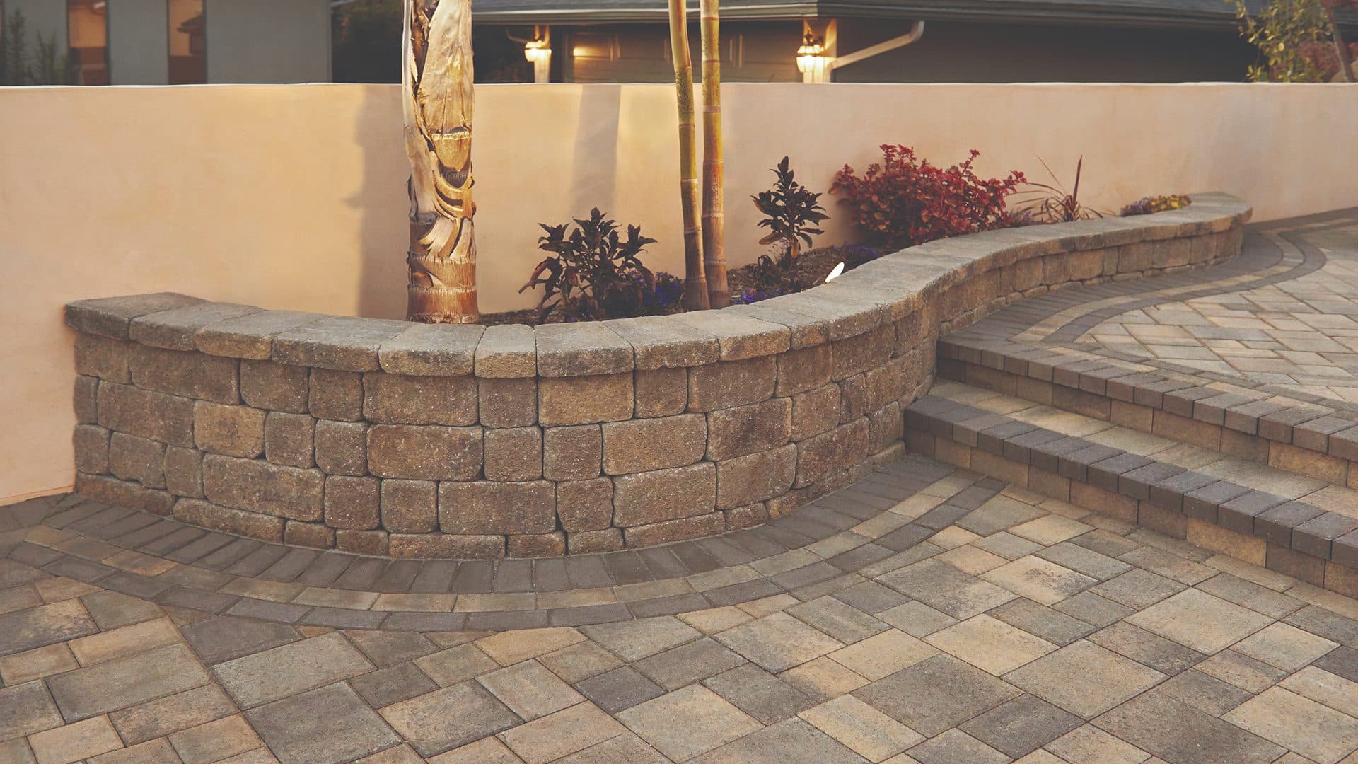 Tan curved seat wall with lantern columns on an interlocking paver patio