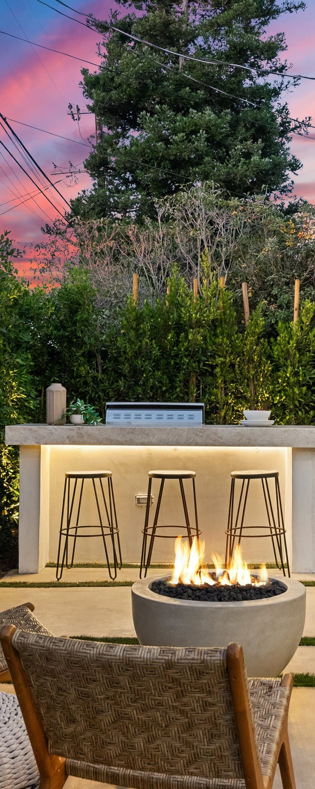 Outdoor dining set on low-water turf framed by green privacy hedges