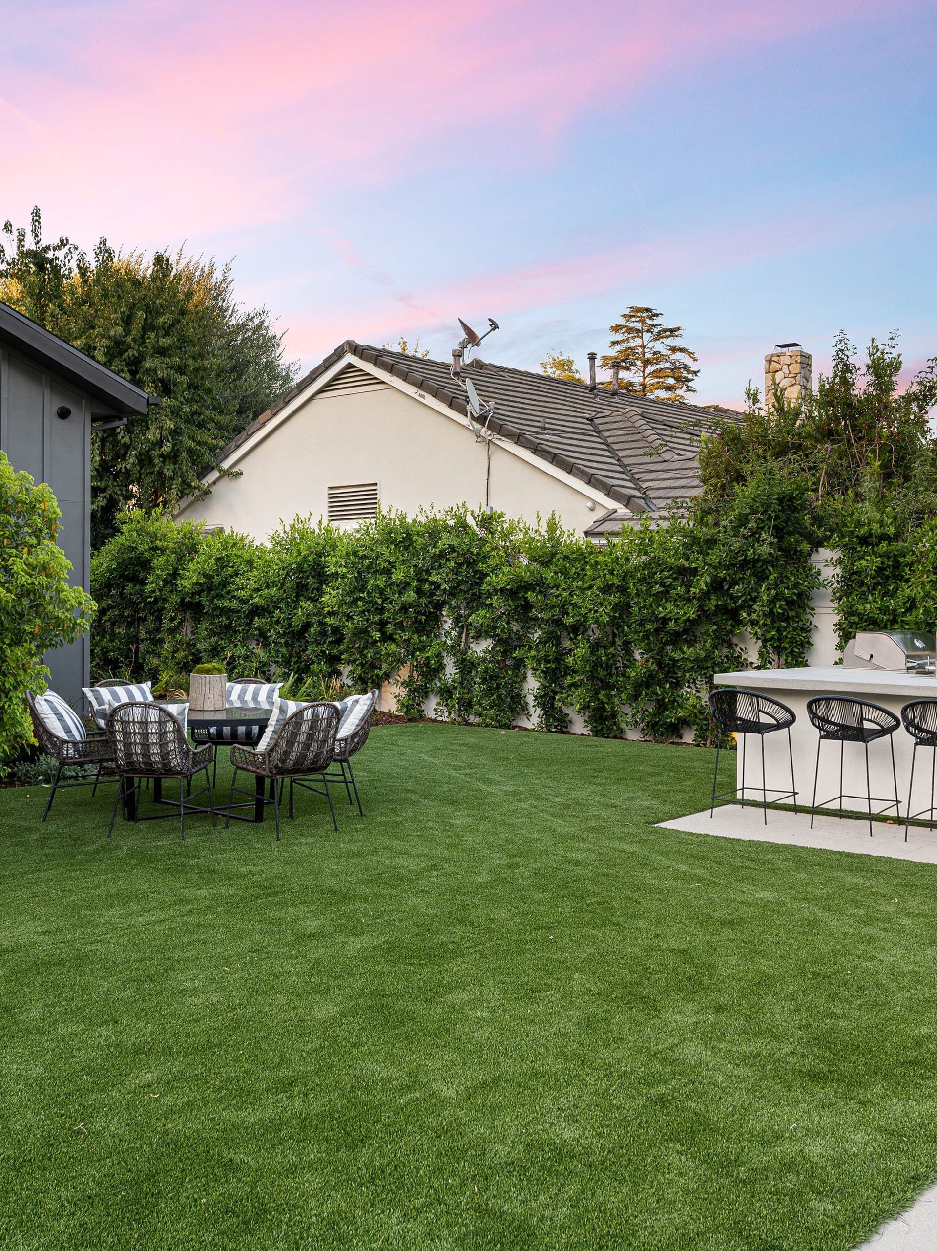 Black board-and-batten modern home entry with oversized concrete pavers and turf joints at dusk