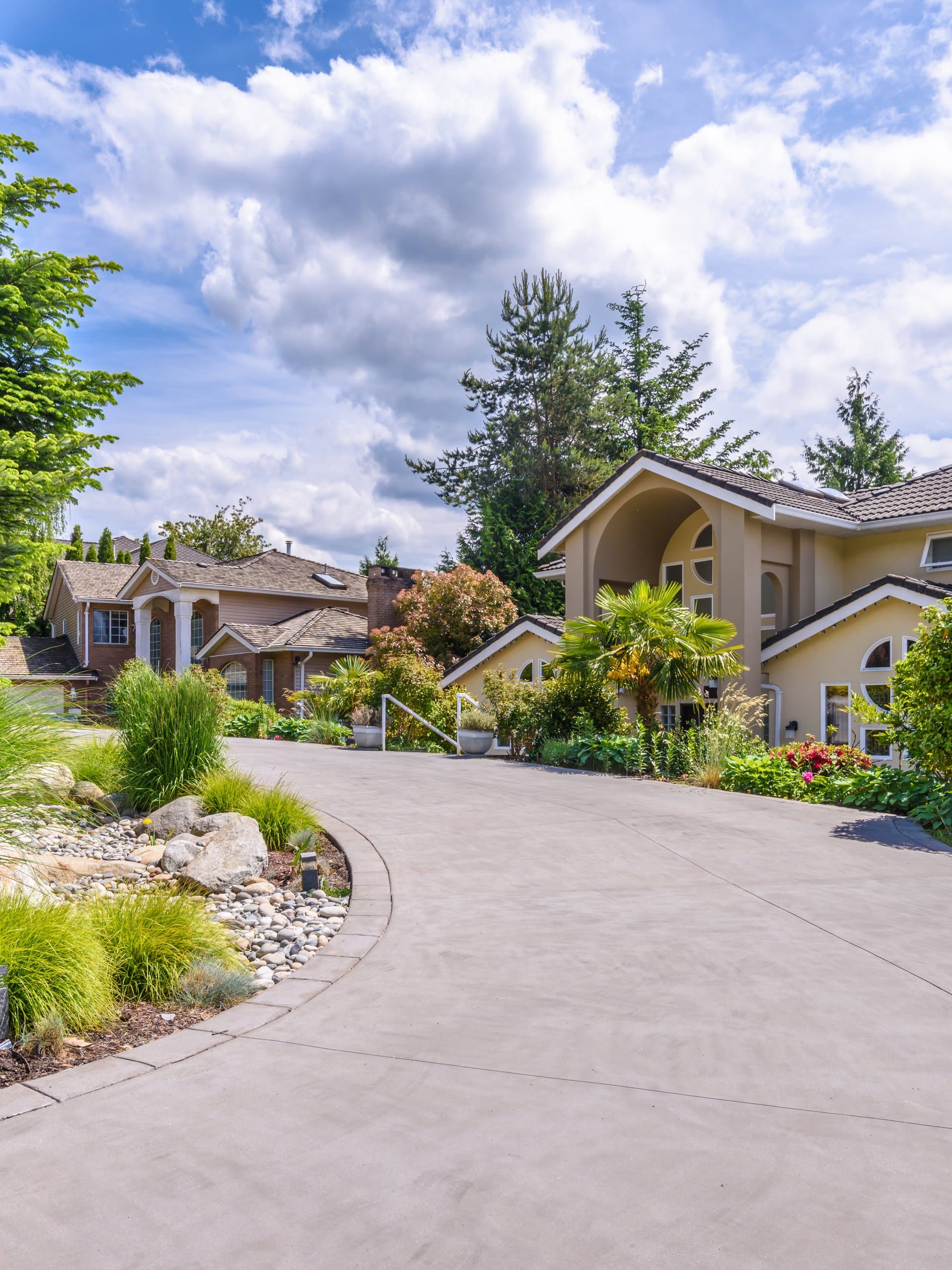 Home at dusk with a brushed concrete driveway beside lawn and mulched beds