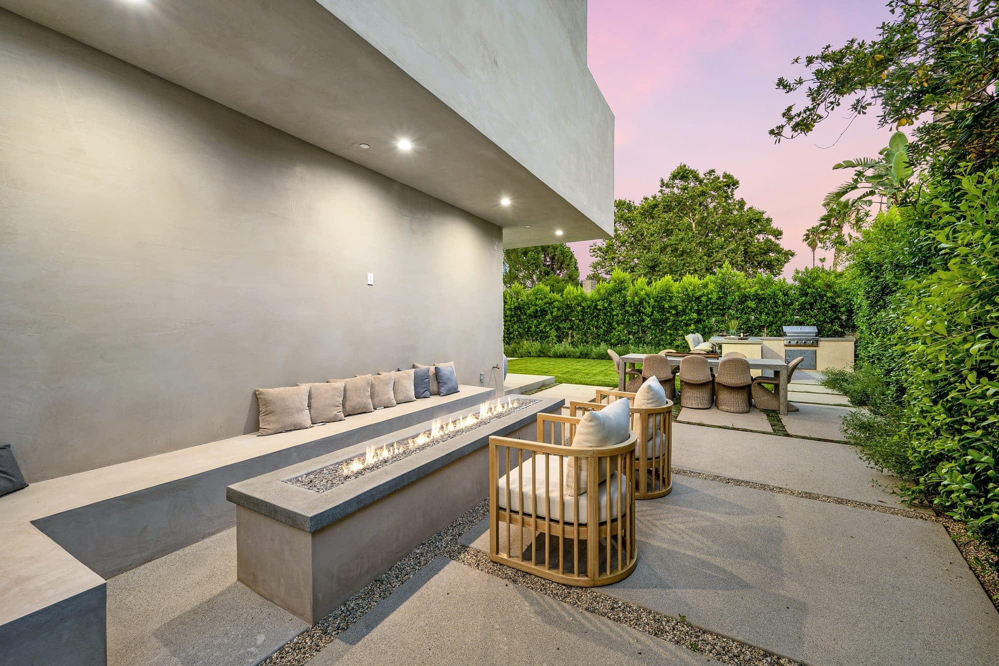 Cast concrete bench and fire feature on an evening patio beside a lawn