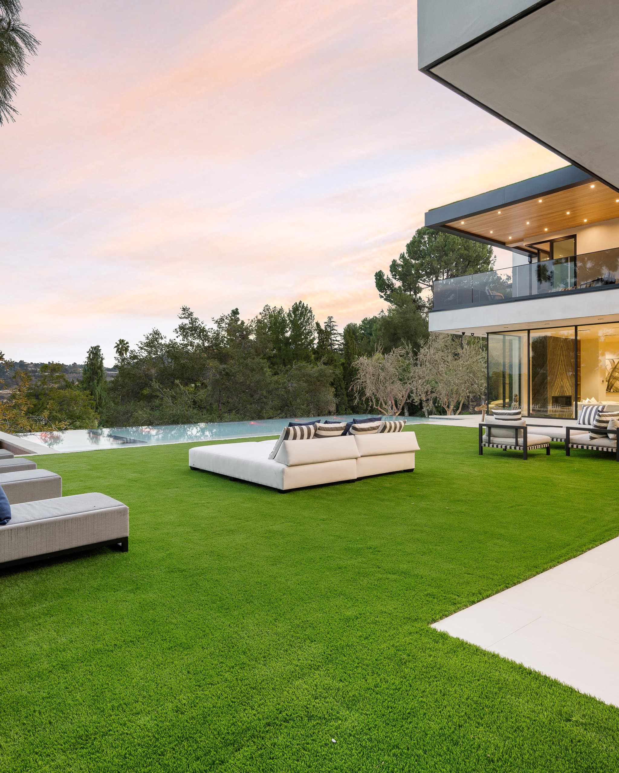 Modern white home with artificial turf lawn and lounge seating at sunset