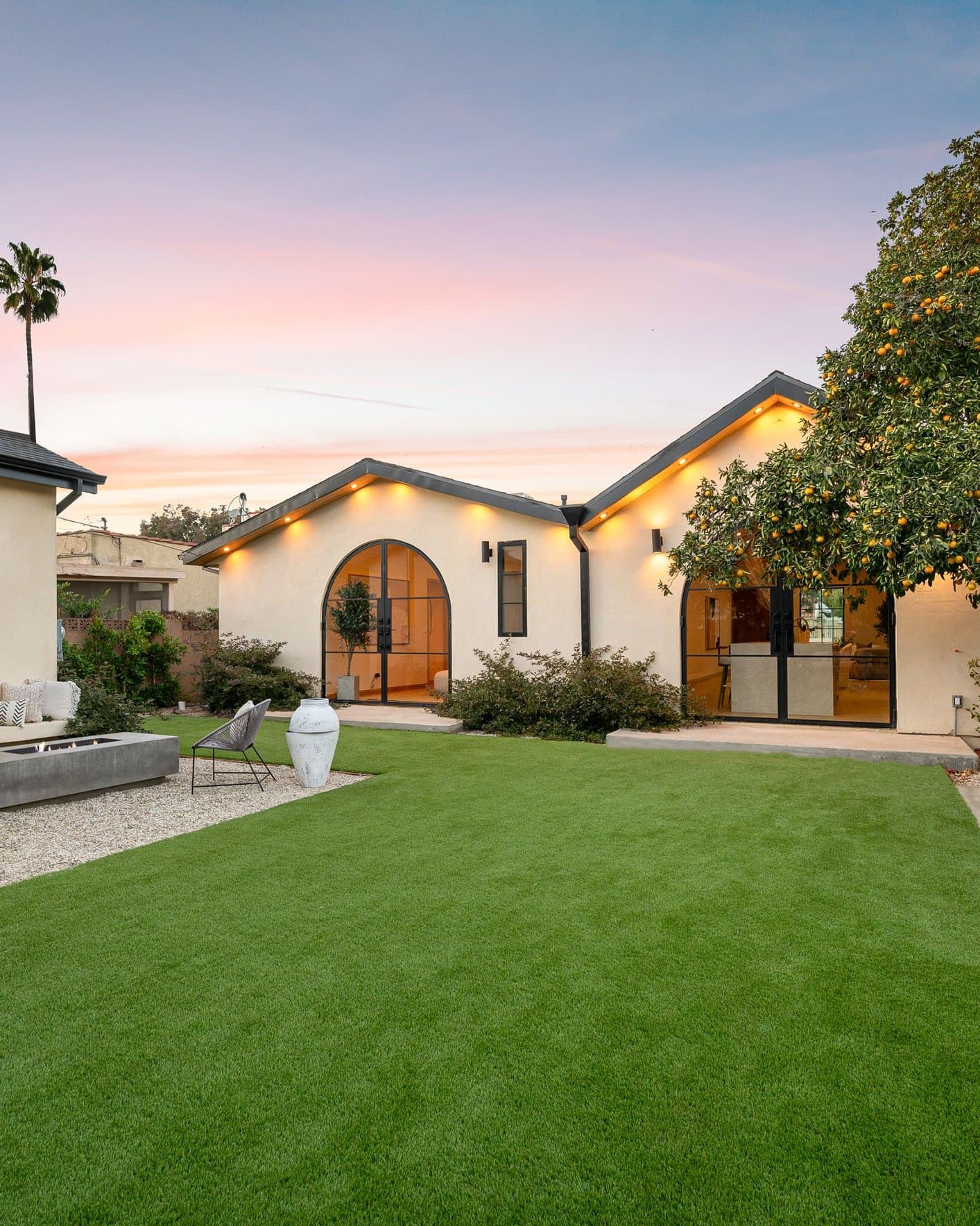 Spanish-style courtyard in the evening with a turf lawn and patio seating