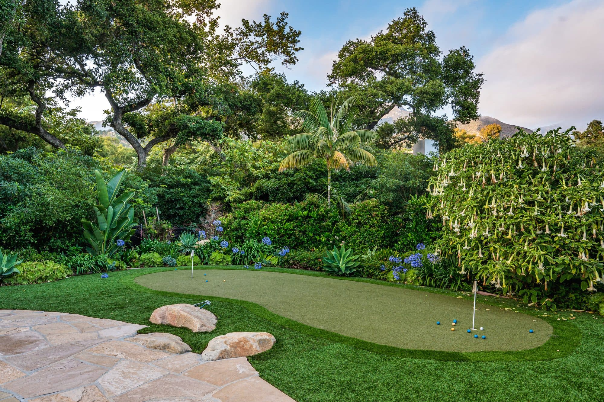 Backyard putting green ringed by boulders and lush planting